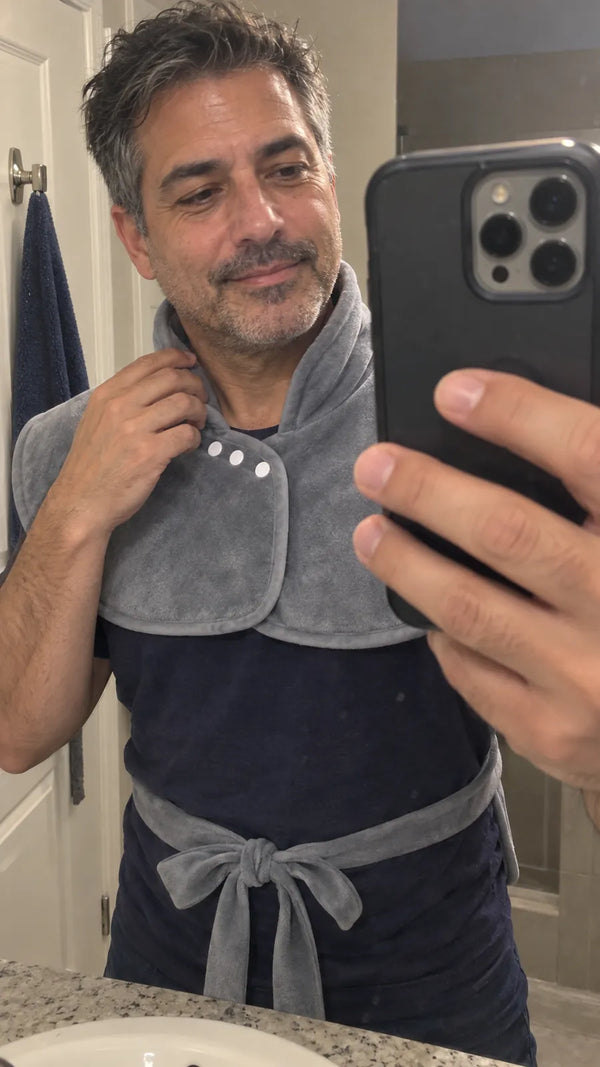 A man taking a bathroom mirror selfie while adjusting the Heatcape collar.